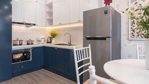 A kitchen with white cabinets, a blue countertop, a stainless steel refrigerator, and a white chair. - Luxury Apartment in Vinhomes D'Capitale by David Home (Hanoi)