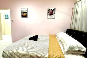 A hotel room with a bed, a headboard, and two framed pictures on the wall. - Corner Lot Taman Bahagia Batu 7 ( 2Minutes to Airport) (Sandakan)