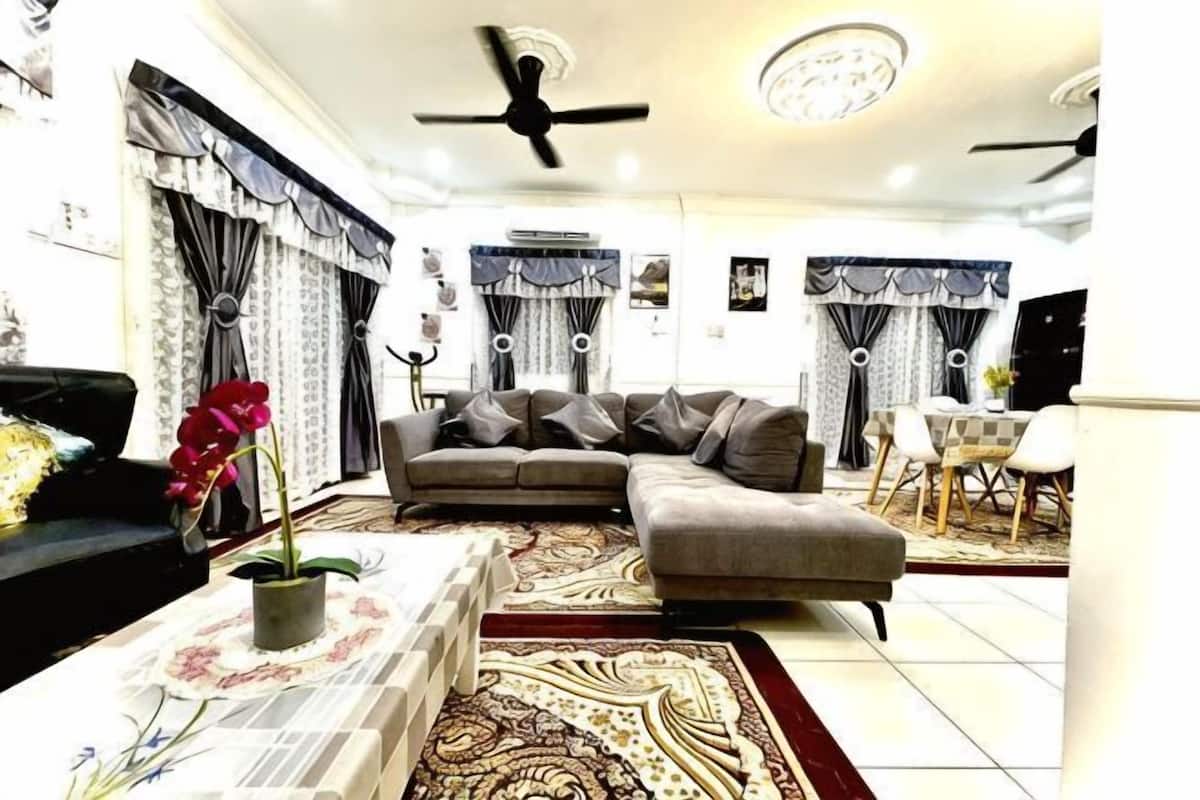 Un salon comprenant un canapé, une table basse avec un vase, un tapis à motifs et un coin repas avec des chaises et une table.