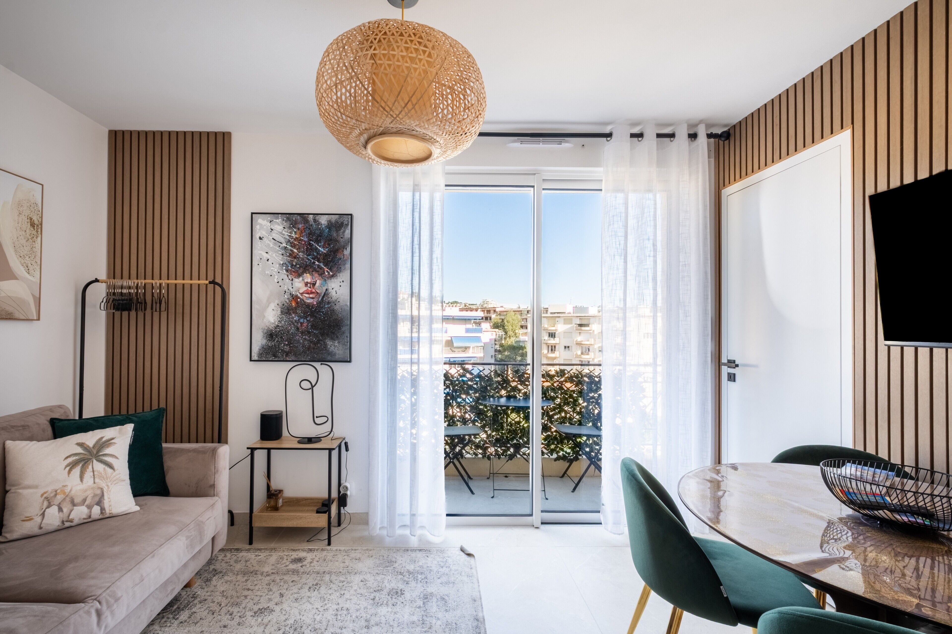 Een moderne woonkamer met een bank, een eettafel, een televisie en een balkon met uitzicht.