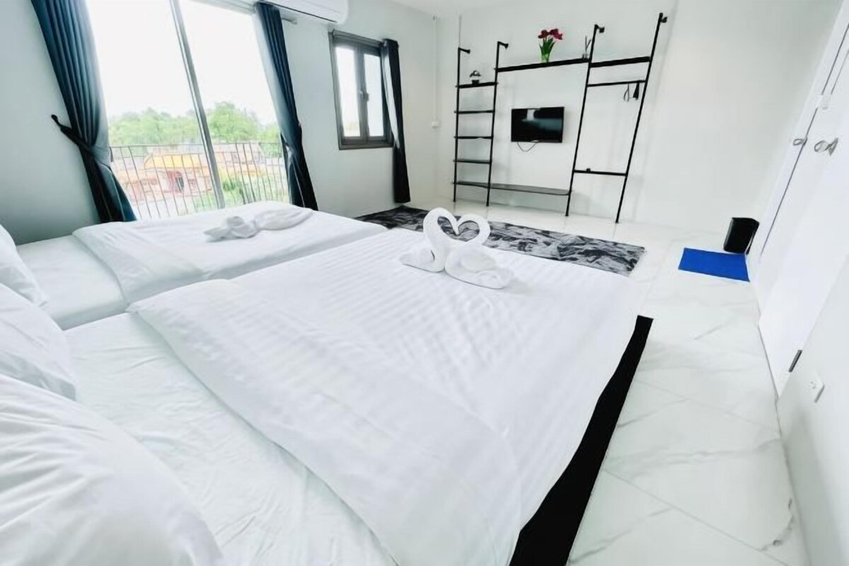 A hotel room with two beds, a TV, a balcony, and a view of the outside.