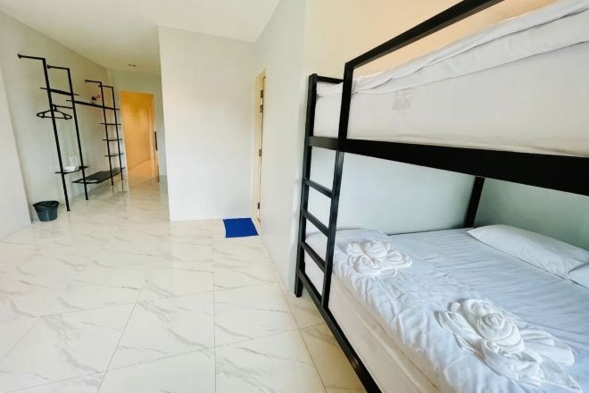 A bunk bed room with a ladder, a blue mat, and a white tiled floor.