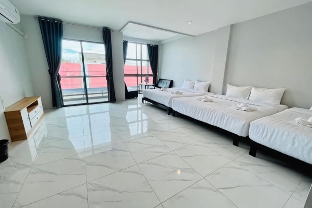 A hotel room with a large bed, a desk, and a view of the outside.