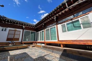 A traditional Japanese building with a wooden exterior, large windows, and a stone courtyard. - Traditional House Hotel Andong Villa (Andong-si)