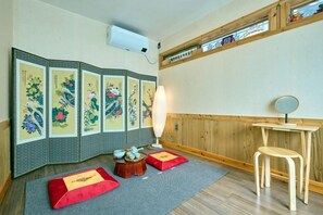 Una habitación japonesa tradicional con suelo de tatami, un shoji, una mesa baja de tatami, un taburete de madera y una mesita con un espejo.