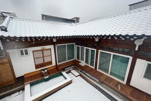 A traditional Japanese-style building with a tiled roof, wooden exterior, and a small outdoor seating area. - Traditional House Hotel Andong Villa (Andong-si)