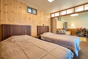 A room with two beds, wooden paneling, a small window, a sofa, and a lamp. - Traditional House Hotel Andong Villa (Andong-si)