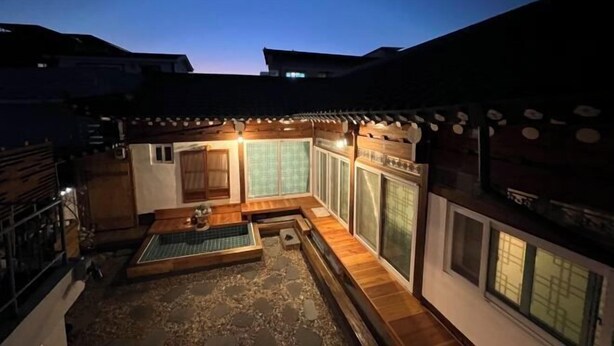 A traditional Japanese-style courtyard with tatami mats, a wooden bench, and a small hot spring area. - Traditional House Hotel Andong Villa (Andong-si)