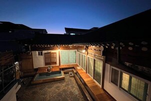 A traditional Japanese-style building with tatami flooring, a wooden deck, and a view of the sky.