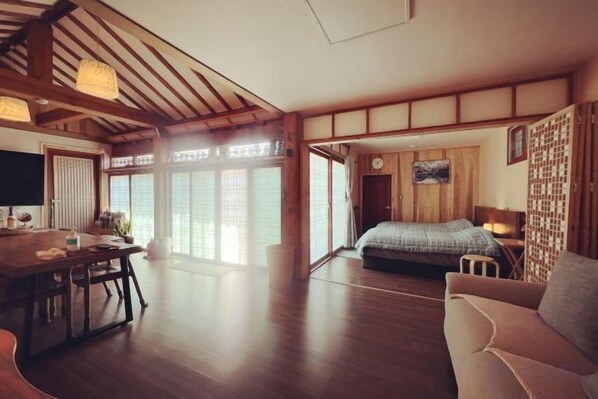 A traditional Japanese-style room with tatami flooring, a low table, a sofa, and a bed with a futon. - Traditional House Hotel Andong Villa (Andong-si)