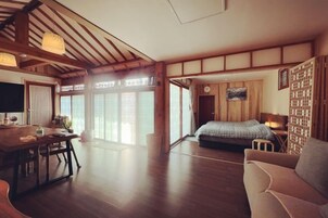 A traditional Japanese-style room with tatami flooring, a low table, a sofa, and a bed with a futon.