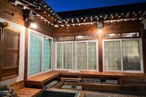 Un onsen japonés tradicional con arquitectura de madera, amplias puertas correderas y una zona de aguas termales de piedra.