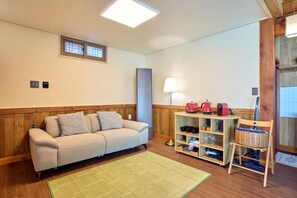 A room with a sofa, a lamp, a shelf with shoes, and a chair. - Traditional House Hotel Andong Villa (Andong-si)