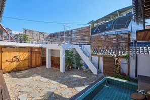 A residential backyard with a swimming pool, wooden deck, and a covered patio area. - Traditional House Hotel Andong Villa (Andong-si)