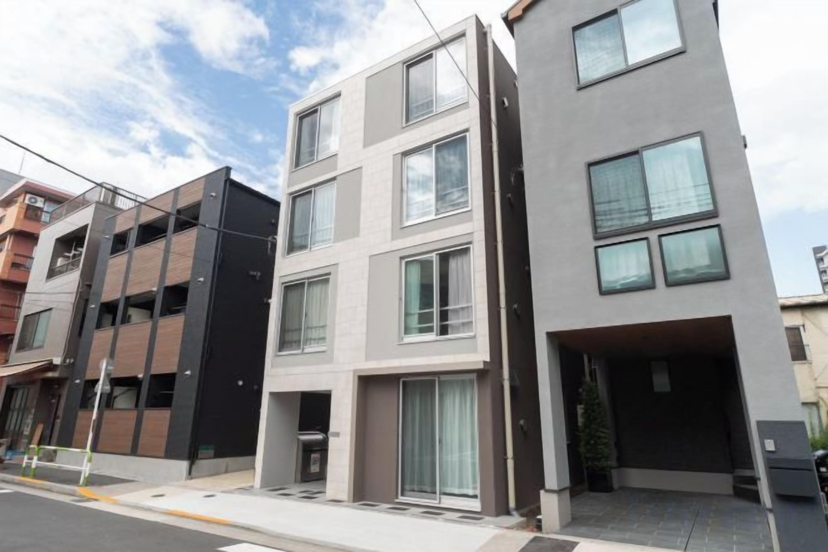 Un edificio residencial de varios pisos con fachada plana, ventanas grandes y entrada visible.