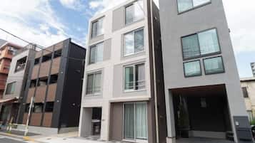 Un edificio residencial de varios pisos con fachada plana, ventanas grandes y entrada visible.