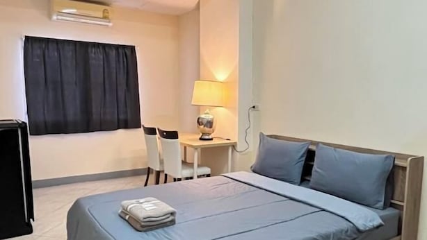 A hotel room with a bed, a desk, a chair, a lamp, and a TV. - ST Residence@Rayong (Pluak Daeng)
