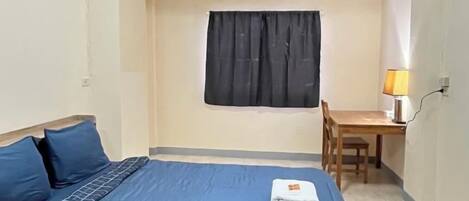 A room with a bed, a desk, a chair, and a window with curtains.