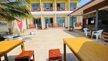 A hotel with outdoor seating, a pool, and a two-story building with balconies.