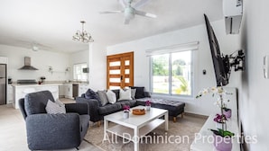 A modern living room with a grey sofa set, a white coffee table, and a large window. - Sosua Ocean Village, Villas 24 (Sosúa)