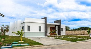 A modern two-story house with a flat roof, a stone wall, and a well-maintained lawn. - Sosua Ocean Village, Villas 24 (Sosúa)
