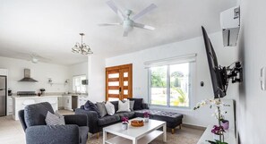 A modern living room with a grey sofa set, a white coffee table, and a large window. - Sosua Ocean Village, Villas 24 (Sosúa)