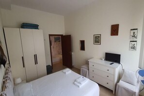 Habitación de hotel con cama, escritorio, armario y televisión.