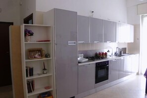 Una cocina moderna con gabinetes blancos, horno integrado y cafetera.