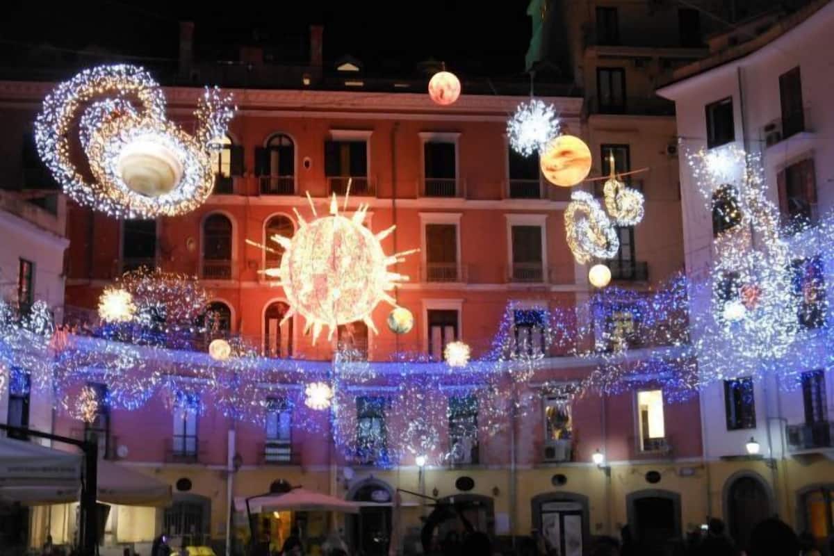 A building facade with multiple windows and balconies, decorated with lights and spherical ornaments.