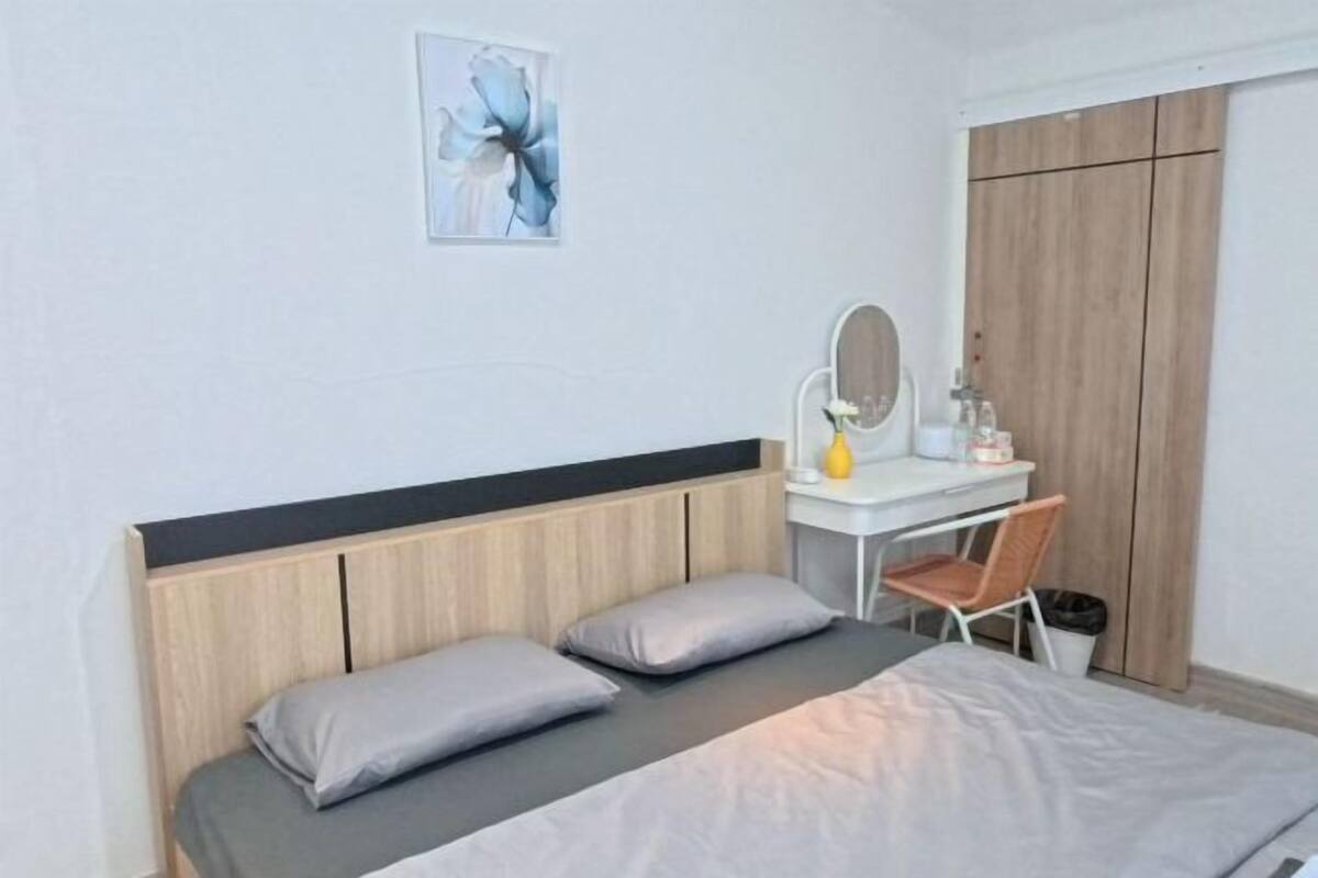 A bedroom with a bed, a desk with a chair, a mirror, and a wardrobe.