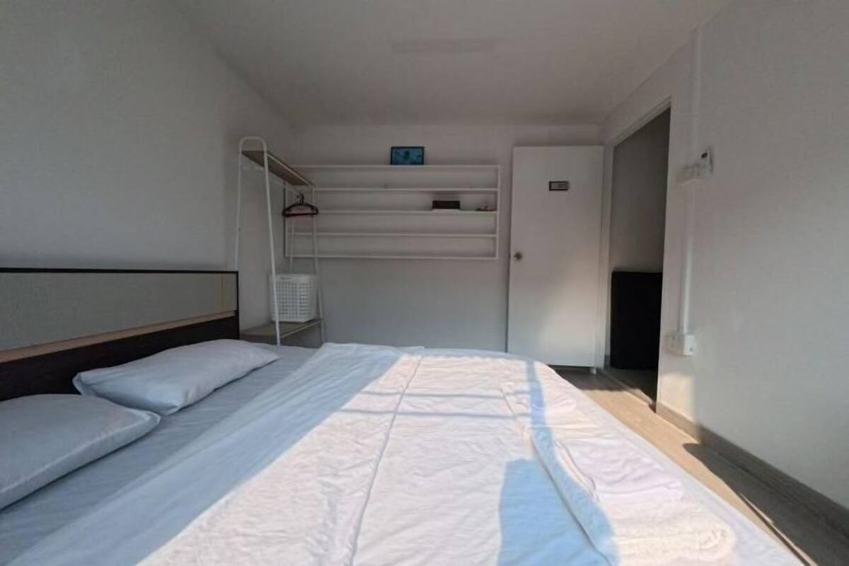 A bedroom with a bed, a wardrobe, a shelf with a clock, and a door.
