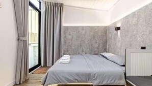 Une chambre moderne avec un lit, une fenêtre avec des rideaux, un luminaire fixé au mur et un radiateur.