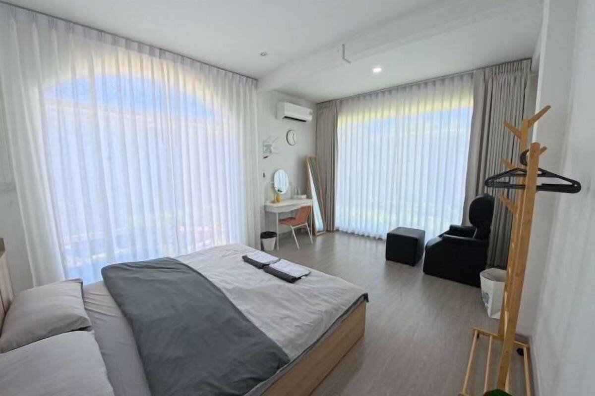 A modern hotel room with a large bed, a desk, a chair, and a coat rack.
