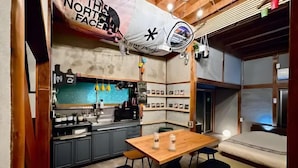 A compact kitchen with a dining area, a bed, and a large window.