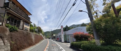 A street with a clear road, a building with a balcony, and a utility pole.