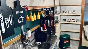 A kitchen area with hanging utensils, a coffee machine, and a small stove.