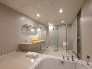 Un baño moderno con bañera, lavamanos, espejo y ducha con mampara de vidrio.