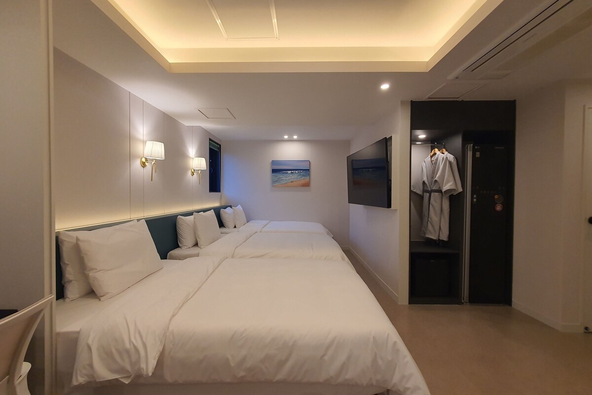 Una habitación de hotel con una cama grande, un armario, un televisor y un cuadro en la pared.