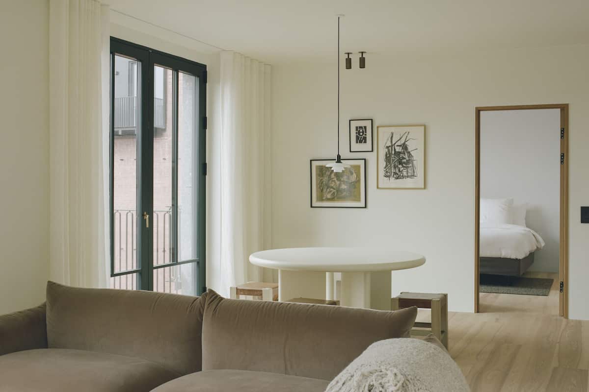 Una sala de estar moderna con un sofá, una mesa redonda y una cama al fondo.