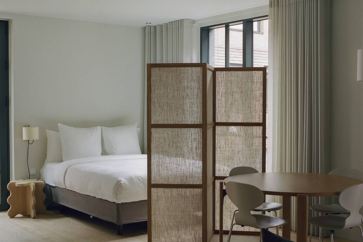 Una habitación de hotel con cama, escritorio, silla, mesita y sofá.