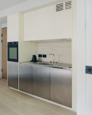 Una cocina moderna con electrodomésticos de acero inoxidable, un lavamanos doble y armarios blancos.