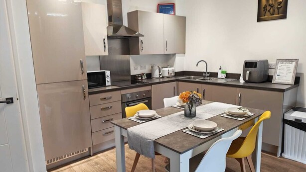 Una cocina moderna con comedor, que incluye microondas, estufa, fregadero y un cartel de bienvenida.