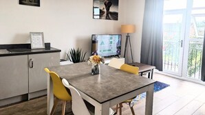 Una habitación moderna con una mesa de comedor, sillas, televisor, lámpara y vistas al exterior.
