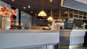 Uma área de bar moderna com balcão, luminárias pendentes e objetos decorativos.