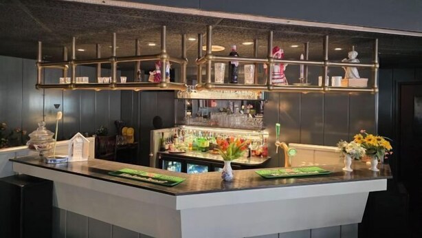 Uma área de bar com balcão, prateleiras e diversos itens de bar.