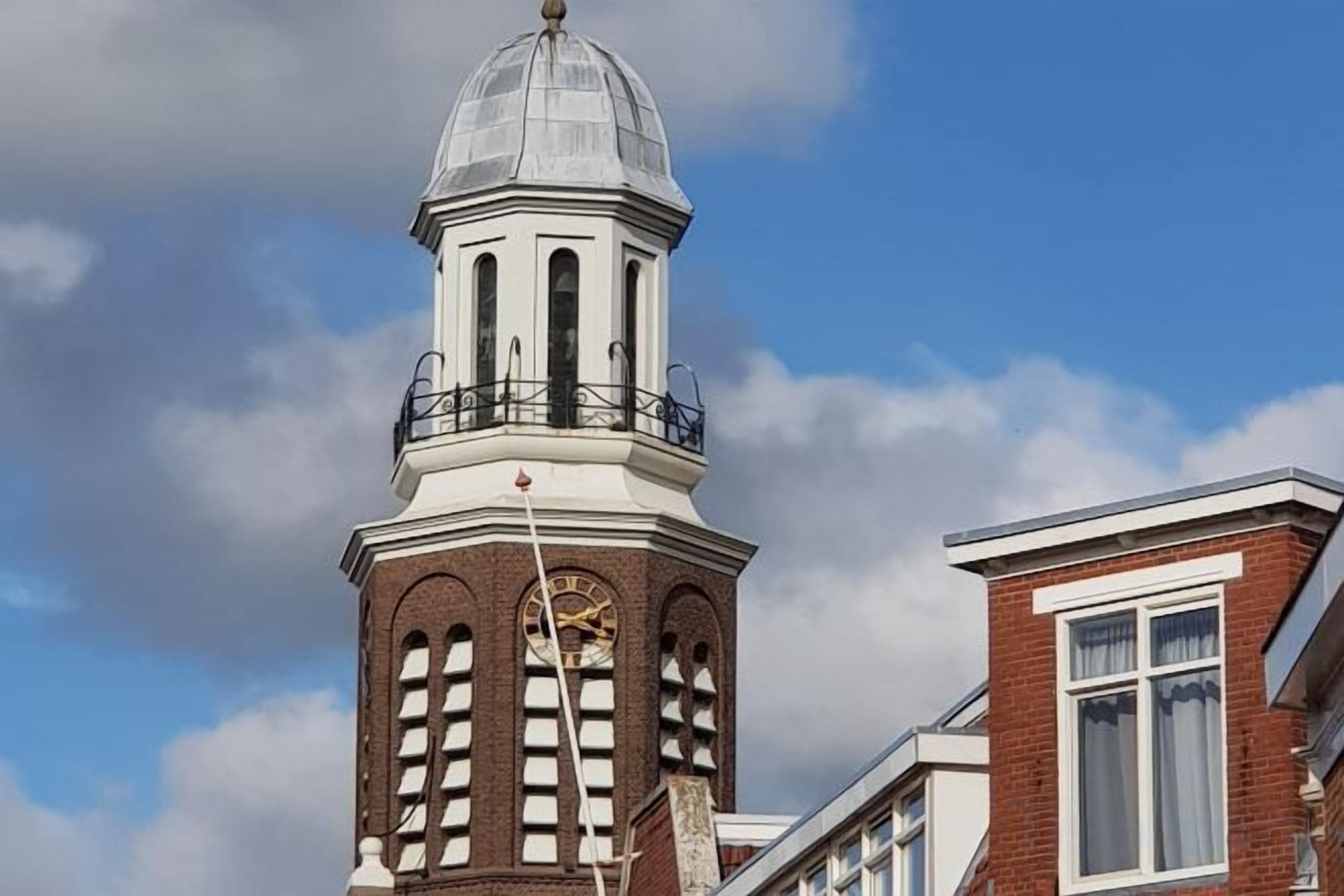 A building with a clock tower featuring a dome and a balcony.