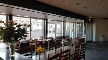 A restaurant with tables and chairs, large windows, and a view of the street.
