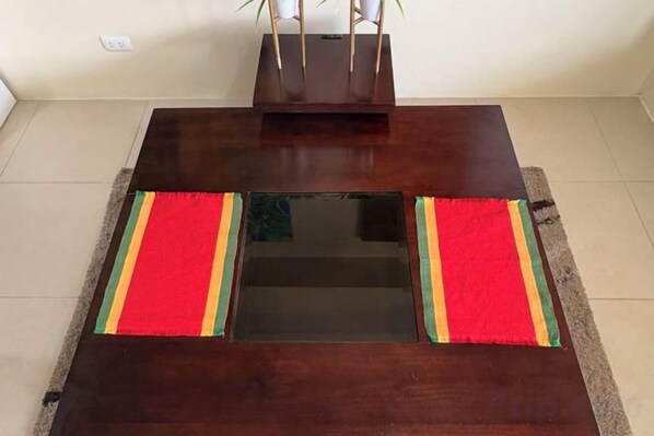 Une table en bois foncé, avec un plateau en verre et des sets de table rayés rouges et verts de chaque côté.