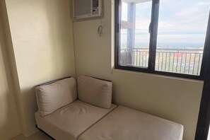 Une petite chambre avec un lit simple et une fenêtre donnant sur l’extérieur.