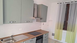 A compact kitchen with grey cabinets, a stainless steel sink, and a black dishwasher. - Kibou Apartment (Garbagnate Milanese)